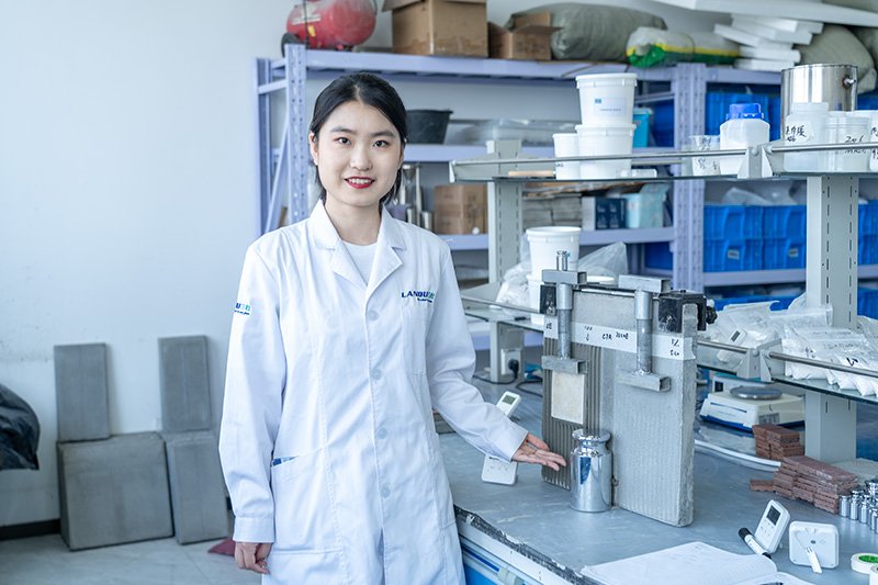 LANDU application technician beside tile adhesive test panels and laboratory equipment