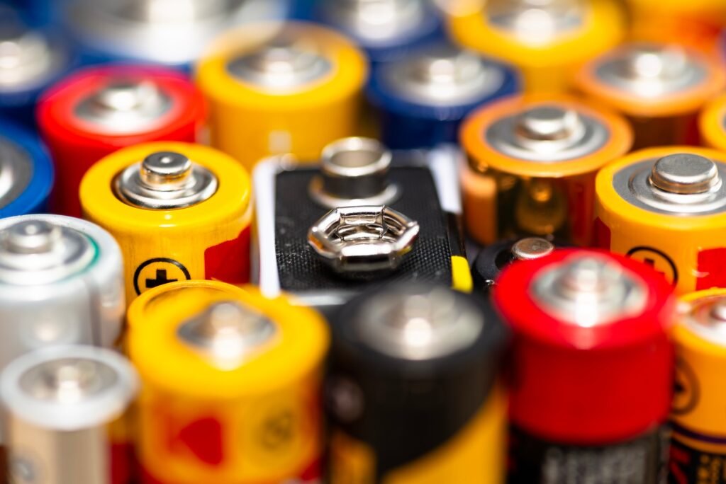 Background made of various alkaline and lithium-ion batteries, positive pole visible.