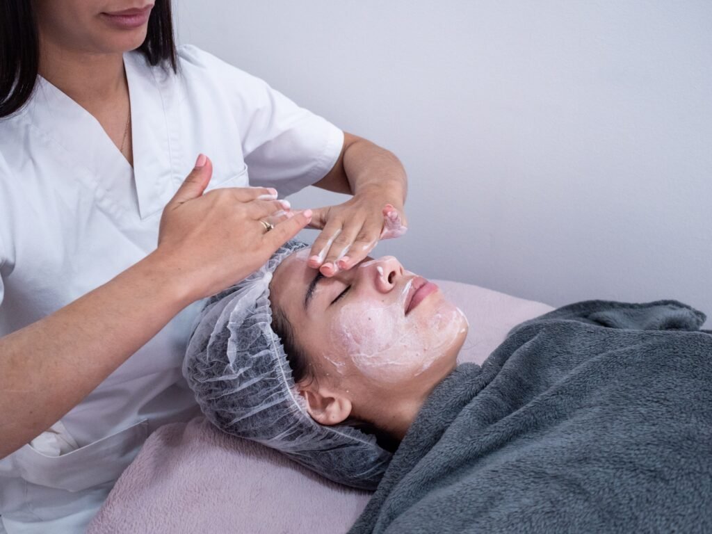 Beauty expert performs facial treatment on client in spa, applying a cleanser