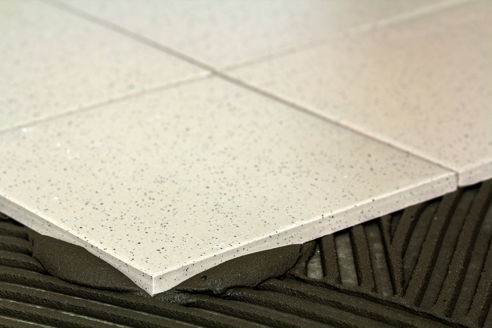 Ceramic floor tile placed over freshly combed tile adhesive ridges