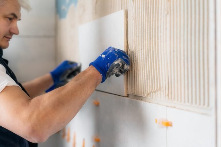 man laying tiles on a bathroom wall. DIY concept. House improvement