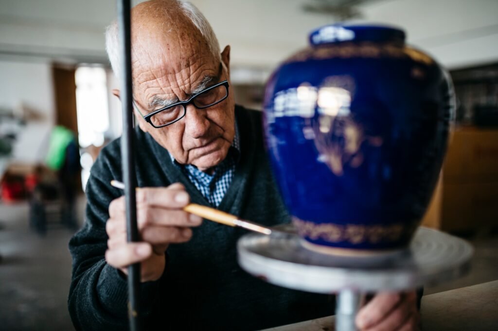 Senior man decorating ceramic vase in his spare time