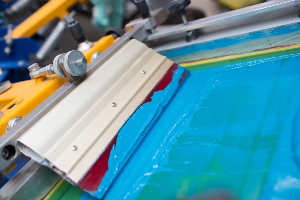 Silk screen printing. Serigraphy. Color paints and fabric. Plastisol paint and squeegee.