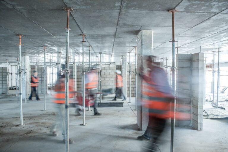 Six blurred construction workers on the go in busy construction site