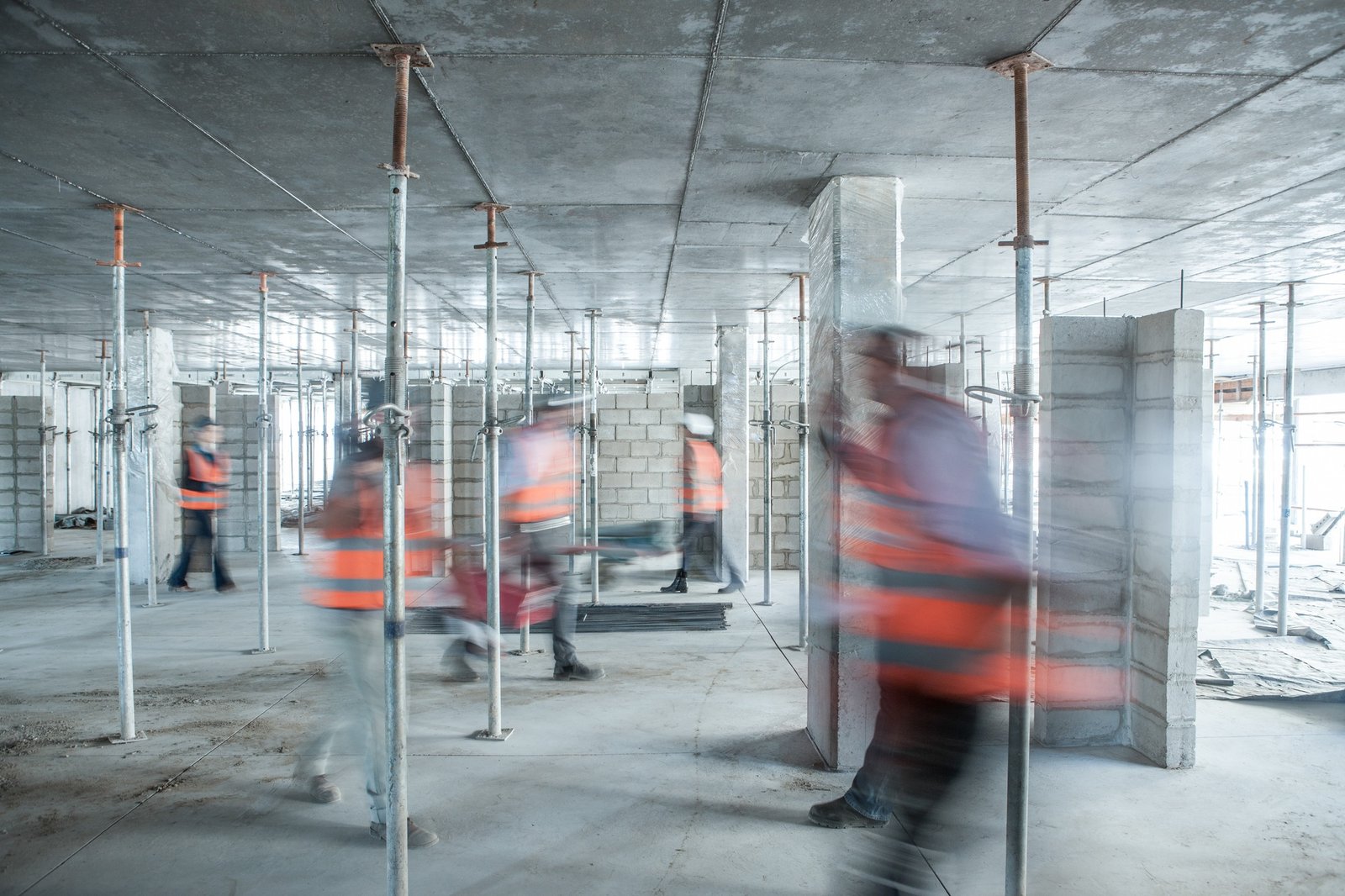Six blurred construction workers on the go in busy construction site