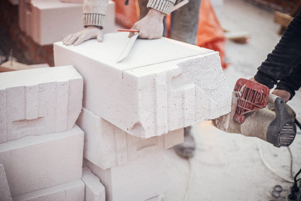 Workers cutting autoclaved aerated concrete block with chainsaw