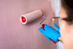 Young woman painting a wall with a paint roller