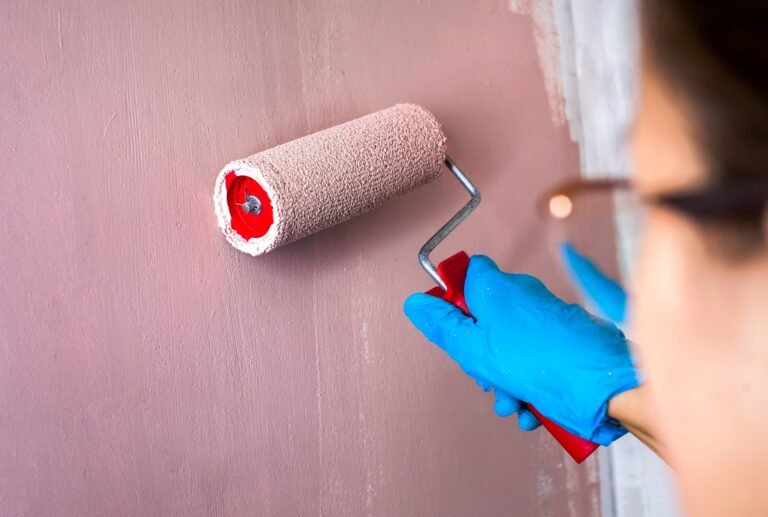 Young woman painting a wall with a paint roller