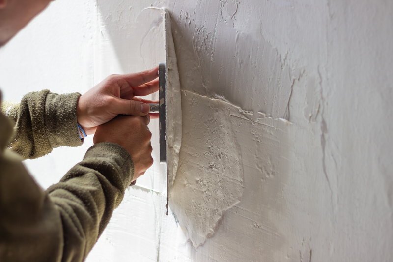 LANDU | Construction worker applying plaster on wall with trowel