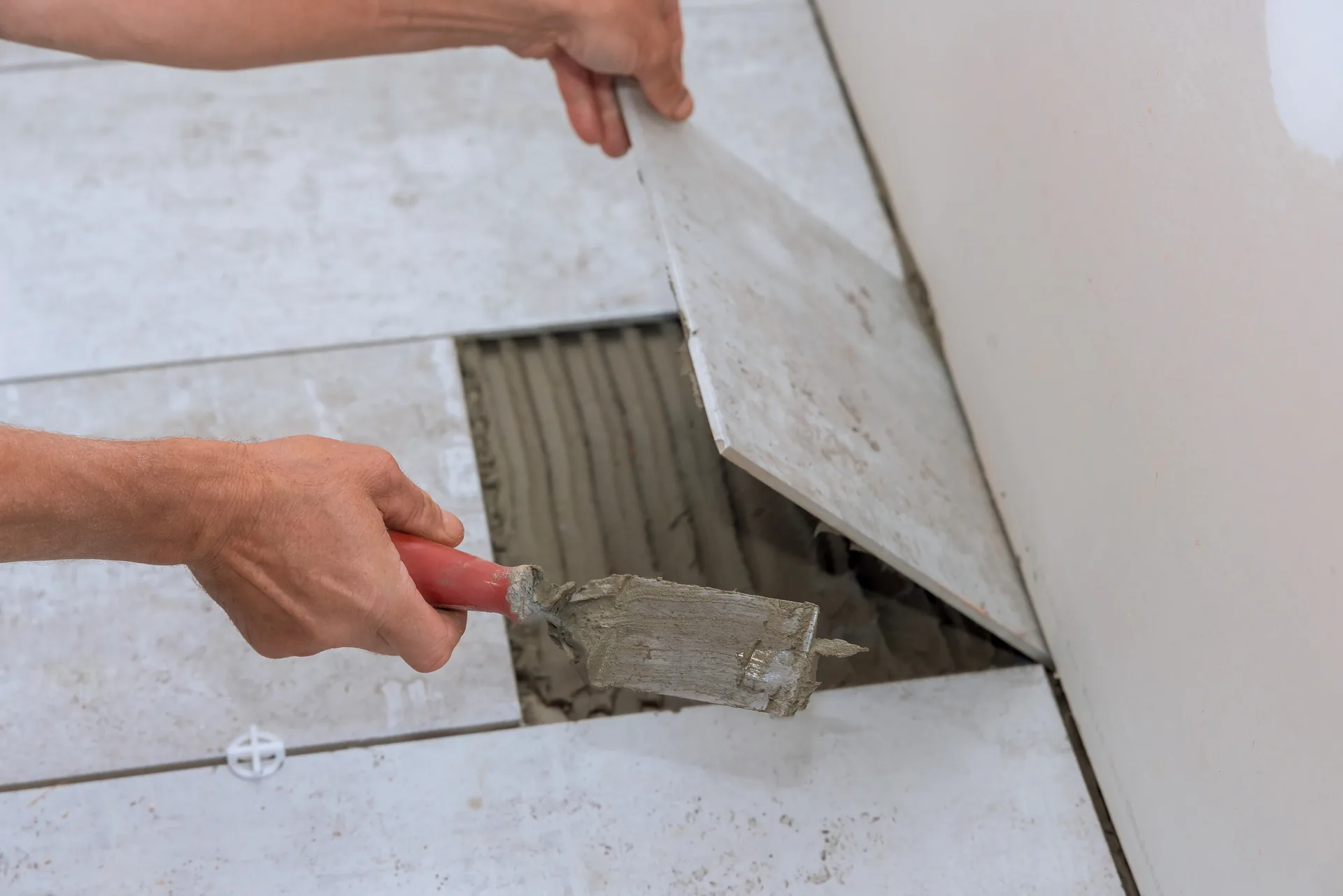 Worker sanding a finished wall surface after joint compound has dried